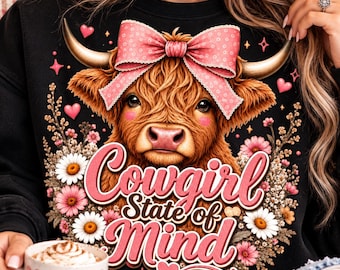 Puede incluir: Una sudadera negra con el gráfico de una vaca Highland marrón que lleva un gran lazo rosa de lunares entre los cuernos. El diseño incluye flores rosas y blancas, pequeños corazones rosas y el texto Cowgirl State of Mind en letra rosa.