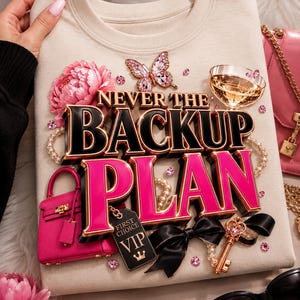 May include: A beige crewneck sweatshirt featuring a graphic print with the text NEVER THE BACKUP PLAN. The design includes a pink peony, a crystal butterfly, a champagne glass, a pink handbag, a black VIP tag, a black bow, and a gold key.