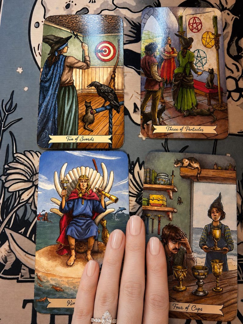 Puede incluir: Cuatro cartas de tarot dispuestas en una cuadr&iacute;cula, incluyendo Dos de Espadas, Tres de Oros, Rey de Copas y Cuatro de Copas. Las cartas presentan ilustraciones detalladas de figuras, animales y objetos simb&oacute;licos con t&iacute;tulos en la parte inferior.