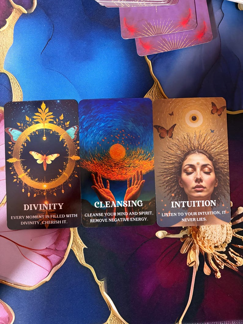 Puede incluir: Tres cartas de or&aacute;culo rectangulares con ilustraciones vibrantes. La primera muestra una mariposa dorada en un c&iacute;rculo con el texto DIVINITY. La segunda muestra manos sosteniendo un sol brillante con el texto CLEANSING. La tercera muestra a una persona con un aura de rayos solares y el texto INTUITION.