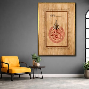 Puede incluir: Gran obra de arte enmarcada con caligrafía árabe en rojo y negro sobre fondo beige. La obra de arte está en un marco dorado con detalles ornamentados. La caligrafía está centrada dentro de un borde decorativo.