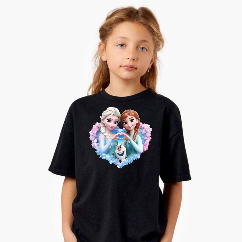 May include: Black t-shirt featuring a heart-shaped graphic with Elsa, Anna, and Olaf from the movie Frozen. The graphic has a light blue and pink floral border. The shirt is worn by a young girl.