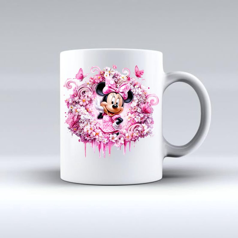 Puede incluir: Una taza de cer&aacute;mica blanca con un gr&aacute;fico central de un personaje de rat&oacute;n de dibujos animados que lleva un lazo rosa de lunares. El personaje est&aacute; rodeado por un denso arreglo circular de flores rosas, p&eacute;talos y peque&ntilde;as mariposas con un efecto de goteo.