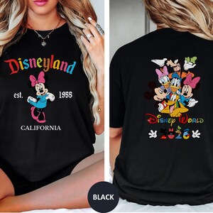 May include: A black t-shirt featuring a front graphic of Minnie Mouse with the text Disneyland est. 1955 CALIFORNIA. The back graphic displays a group of Disney characters with the text Disney World 2026 and small character-themed icons.
