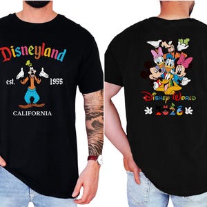 May include: A black short-sleeve t-shirt featuring a front graphic of Goofy with the text Disneyland est. 1955 CALIFORNIA. The back graphic displays a group of Disney characters above the text Disney World and the year 2026 with small icons.