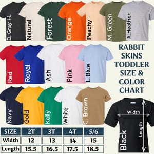 May include: A Rabbit Skins toddler size and color chart featuring twenty-one short-sleeve t-shirts in various colors including dark gray, natural, forest, orange, peachy, military green, ash, heather, red, royal, pink, light blue, navy, gold, kelly, white, brown, and black. A size table displays width and length measurements in inches for sizes 2T, 3T, 4T, and 5/6.