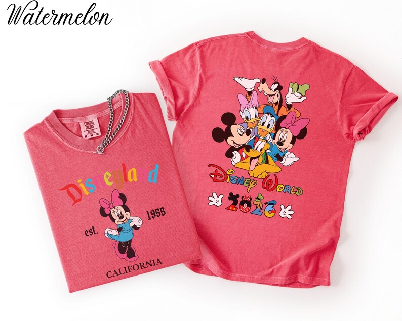 May include: Two watermelon-colored t-shirts. The left shirt features Minnie Mouse with the text Disneyland est. 1955 CALIFORNIA. The right shirt displays a group of Disney characters with the text Disney World 2026 and colorful accents.