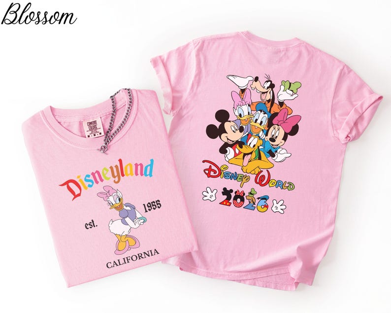 May include: Two light pink t-shirts. The left shirt features Daisy Duck, the text Disneyland est. 1955 CALIFORNIA. The right shirt displays a group of Disney characters, the text Disney World 2026, and two white glove icons on a light pink background.