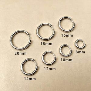 May include: A collection of silver-colored hoop earrings in various sizes, ranging from 8mm to 20mm in diameter. Each earring is a simple, circular design with a hinged closure. The sizes are labeled on the image.