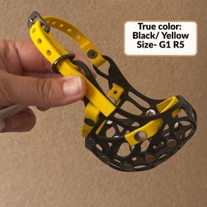 May include: A black and yellow dog muzzle featuring a cage-like design with silver-toned rivets and an adjustable yellow strap with a metal buckle. The text on the image reads: True color: Black/ Yellow Size- G1 R5. The muzzle has a flexible structure.