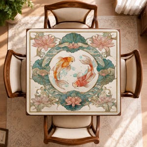 May include: A square table featuring a decorative top with a central circular motif of two orange and white koi fish swimming in a circle. The design includes light pink lotus flowers and teal lily pads arranged in a symmetrical border pattern.