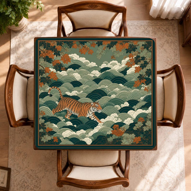 May include: A square table cover featuring a tiger walking through stylised green waves and orange maple leaves. The design is bordered by a thin dark frame, set against a background of repeating wave patterns in shades of teal and sage green.