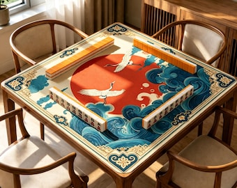 May include: A square mahjong table featuring a play mat with a large red sun, white cranes, and blue stylized waves. Four rows of orange and white mahjong tiles are arranged in a square formation on the mat. The table is made of wood.