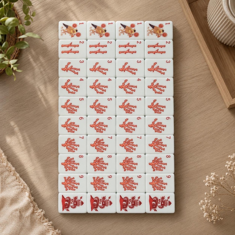 May include: A set of white rectangular mahjong tiles arranged in a grid, featuring red illustrations of coral branches numbered one through nine, with a bird graphic on the top row and a lighthouse graphic on the bottom row of each column.