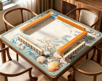 May include: A square wooden mahjong table with a marine-themed design, featuring seashells and ocean waves. The table is surrounded by four wooden chairs. Orange and white mahjong tiles are arranged on the table's surface.
