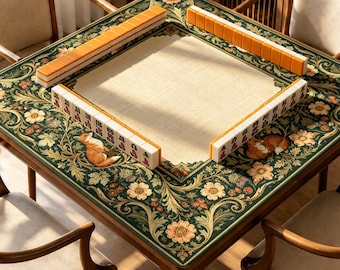 Puede incluir: Una mesa de mahjong cuadrada de madera con una superficie central de tela beige rodeada por un borde verde oscuro con intrincados patrones florales e ilustraciones de zorros. Cuatro filas de fichas de mahjong naranjas y blancas.