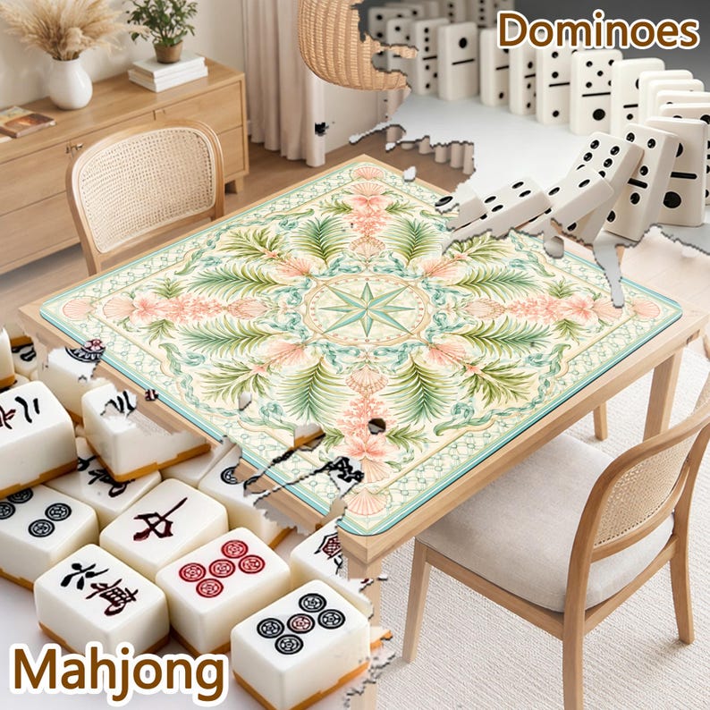 May include: A square table mat featuring a central compass rose surrounded by intricate botanical patterns of green palm leaves and pink floral motifs. The mat is displayed on a wooden table with white mahjong tiles and dominoes visible.