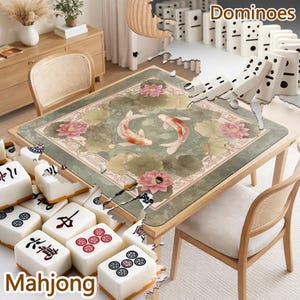 May include: A square game table mat featuring a green background with a central illustration of two koi fish swimming among pink lotus flowers and green lily pads. The mat is surrounded by white mahjong tiles and white dominoes.