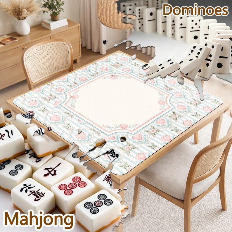 May include: A square table mat featuring a light blue and white striped pattern with pink seashell and floral motifs, surrounded by white mahjong tiles with black and red characters and white dominoes with black pips on the table surface.