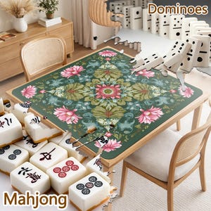 May include: A square table mat featuring a dark green background with a symmetrical floral pattern of pink lotus flowers and green leaves. The mat is surrounded by white mahjong tiles with black and red symbols and white dominoes with black dots.