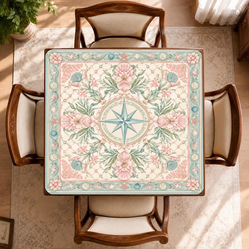 May include: A square table featuring a central compass rose design surrounded by intricate floral and seashell motifs in soft shades of pink, teal, and cream. The border displays a repeating pattern of shells and flowers on a light blue background.