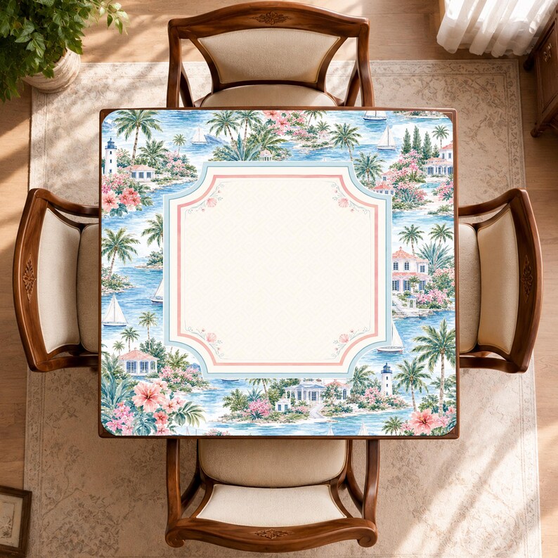 May include: A square table featuring a coastal scene with palm trees, lighthouses, sailboats, and pink flowers. The center of the tabletop has a large, blank, cream-colored rectangular panel with rounded corners, framed by a light blue and pink border.