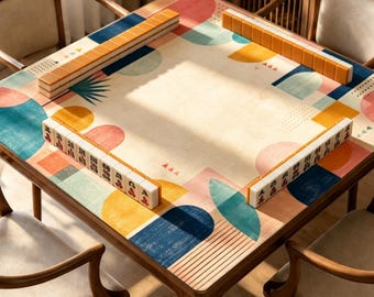Może przedstawiać: Kwadratowy drewniany stół przykryty matą we wzory geometryczne w kolorach niebieskim, żółtym i różowym. Cztery rzędy płytek mahjong są ułożone wzdłuż krawędzi stołu, przy czym dwa rzędy pokazują pomarańczowe rewersy, a dwa awersy płytek.