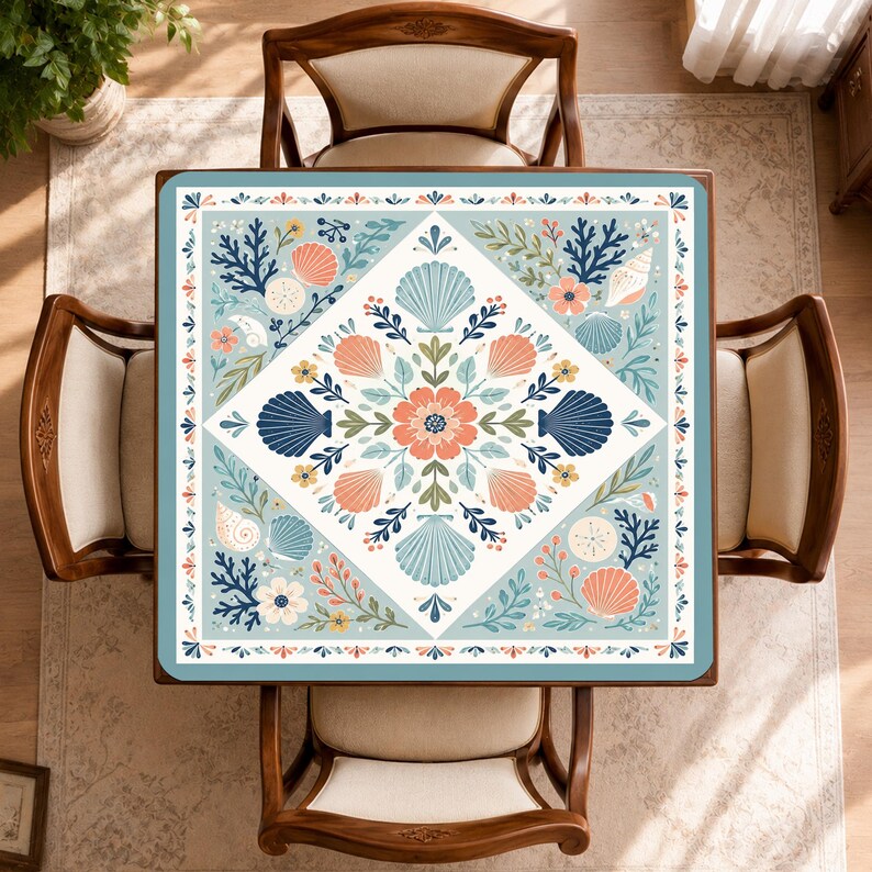May include: A square tablecloth featuring a central diamond pattern filled with coral, navy blue, and light blue seashells, flowers, and leafy sprigs. The border displays a repeating motif of small orange and blue petals on a light blue background.
