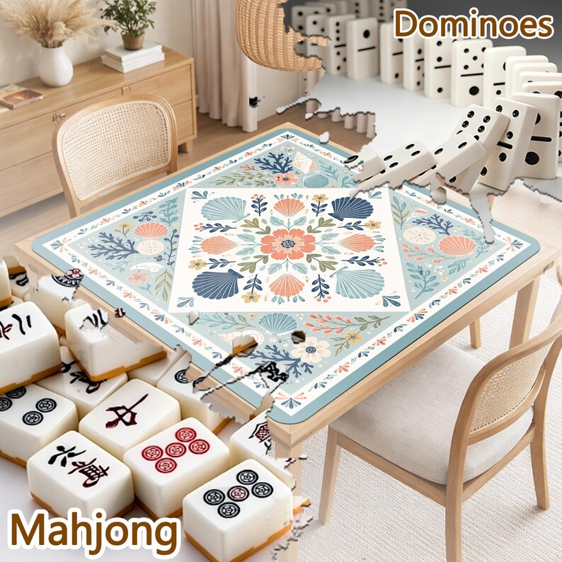 May include: A square table mat featuring a central white square with a floral and seashell pattern in shades of blue, peach, and green, surrounded by a matching border. The mat is displayed on a wooden table with mahjong tiles and dominoes.