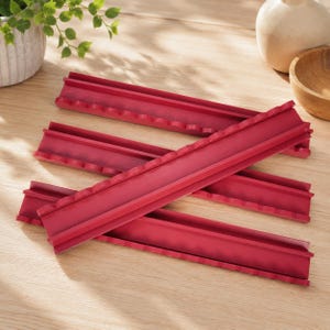 Puede incluir: Un conjunto de cuatro soportes rectangulares de color rojo oscuro, largos, con un borde festoneado en un lado. Cada soporte presenta un canal central a lo largo de la pieza, dise&ntilde;ado con una base plana y lados elevados para sostener objetos.