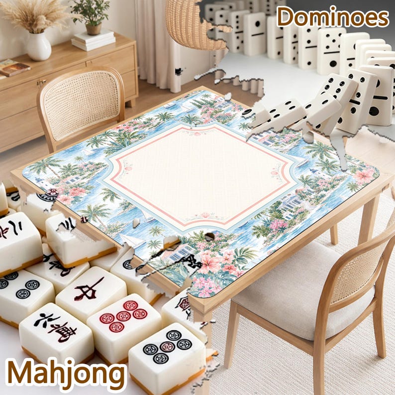 May include: A square game table mat featuring a tropical landscape with palm trees, blue water, and pink flowers, surrounded by white mahjong tiles with black and red symbols and a row of white dominoes with black pips on the table surface.