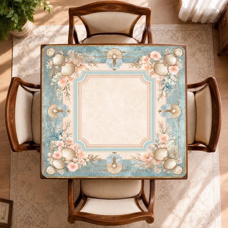 May include: A square table with a light beige center and a decorative border featuring blue tones, white seashells, and soft pink floral accents. The table is surrounded by four wooden chairs with light-colored upholstered seats and backrests.