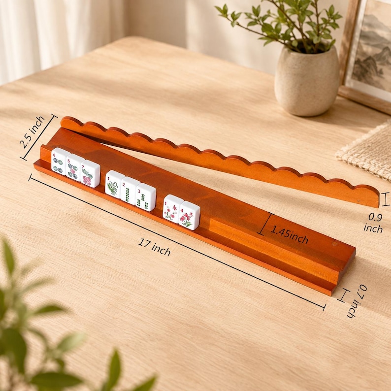 May include: A wooden mahjong tile rack with a scalloped top edge, measuring 43.18 cm in length, 6.35 cm in height, 1.78 cm in depth, and 3.68 cm in width, holding white mahjong tiles with green and red floral and numeric designs.