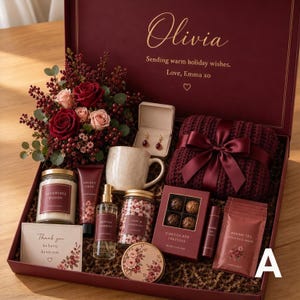 Könnte beinhalten: Eine bordeauxrote Geschenkbox mit einem Strauß aus roten und rosafarbenen Rosen, Ohrringen in einem Etui, einer gesprenkelten Keramiktasse, einem gefalteten kastanienbraunen Strickschal mit Schleife, Kerze, Lotion, Spray, Tee und Pralinen.