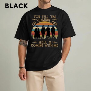 May include: Black t-shirt featuring a graphic with four figures in silhouette, a sunset design, and the text "YOU TELL 'EM I'M COMING AND HELL'S COMING WITH ME." The word "BLACK" is printed at the top.