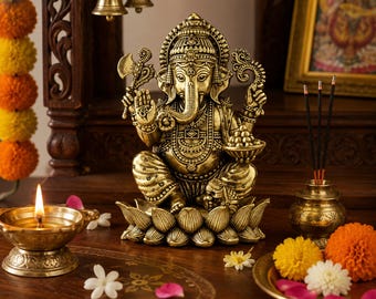 Könnte beinhalten: Eine metallisch goldfarbene Statue der Gottheit Ganesha, die auf einer Lotusblütenbasis sitzt. Die Figur zeigt einen Elefantenkopf, vier Arme, die eine Axt und eine Schale mit Süßigkeiten halten, sowie detaillierten traditionellen Schmuck.