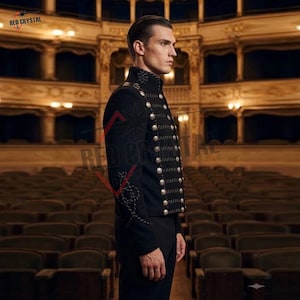 May include: A black military-style jacket featuring a high collar, long sleeves, and a double-breasted front closure with two vertical rows of silver-toned buttons connected by decorative black braided cord detailing across the chest.