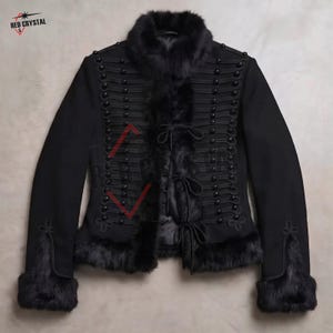 May include: A black jacket featuring a high collar, cuffs, and front trim lined with black fur. The front displays horizontal corded braiding with black spherical buttons and three central tie closures. The text RED CRYSTAL is visible.