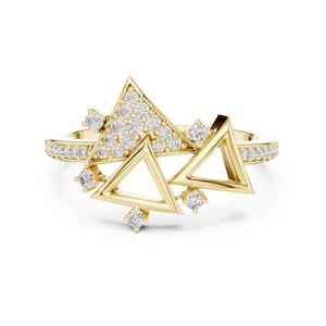 May include: A gold ring featuring a band encrusted with small round clear stones. The centrepiece consists of three geometric triangle shapes, one of which is filled with a cluster of small round clear stones, while the others are open frames.