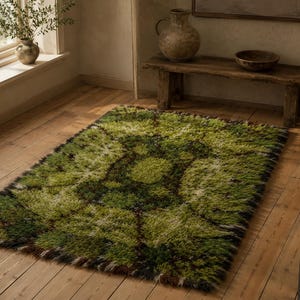 May include: A rectangular area rug featuring a shaggy, high-pile texture with a variegated colour palette of deep forest green, bright lime, olive, and dark brown tones, arranged in a central circular pattern with radiating geometric accents.