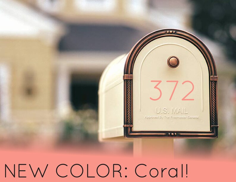 May include: A white mailbox with a copper colored trim and a coral colored house number "372". The mailbox has a U.S. Mail label and is approved by the Postmaster General.