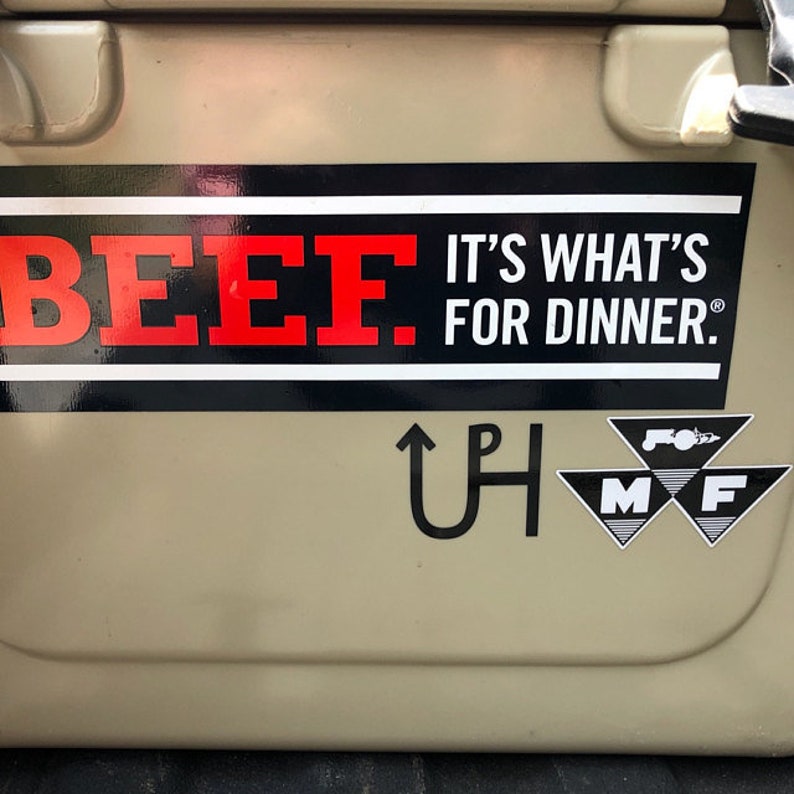 May include: A white cooler with a black and red sticker that says "BEEF. IT'S WHAT'S FOR DINNER." There is a black and white sticker with a horseshoe and the letters "UP" and a black and white sticker with a tractor logo and the letters "MF".