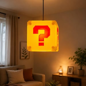 Peut inclure: Une suspension lumineuse carrée en forme de cube jaune avec un point d'interrogation rouge sur chaque face. La lampe est suspendue au plafond par un cordon noir et une fixation circulaire, diffusant une lueur chaude depuis sa structure.