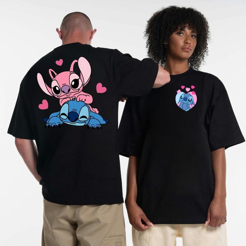 May include: Black t-shirts featuring the characters Stitch and Angel from Lilo & Stitch. One shirt has a large graphic on the back of Stitch and Angel with hearts. The other shirt has a smaller graphic on the front of Stitch and Angel inside a heart.