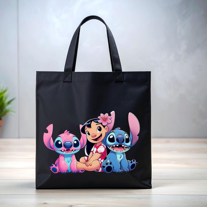May include: Black tote bag featuring a colorful graphic of Lilo and Stitch characters. The design includes Lilo, Stitch, and a pink Stitch. The bag has black handles and is made of a durable material.