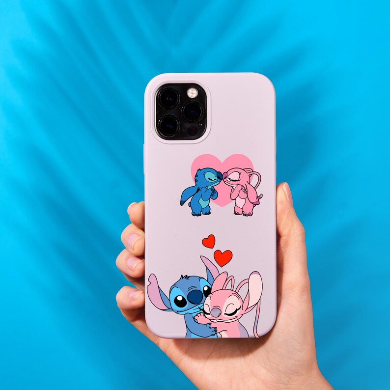 May include: A lavender phone case featuring a cartoon illustration of Stitch and Angel, with hearts. The case has a protective bumper and a camera cutout. The design includes two pairs of the characters, one kissing and the other embracing.