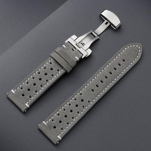 May include: Gray leather watch strap with white stitching and a stainless steel clasp. The strap features a perforated design and is shown against a dark gray background. The watch band is a replacement part for a watch.