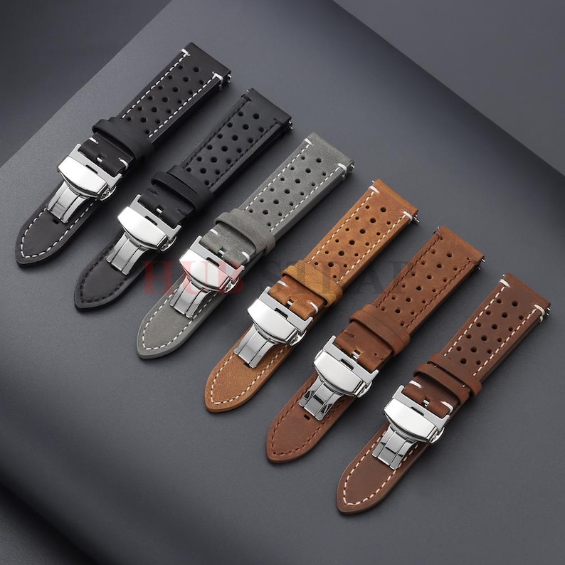 May include: Six watch straps in various colors, including black, gray, and brown. Each strap features a perforated design and a silver-tone clasp. The straps are made of leather and have white stitching.