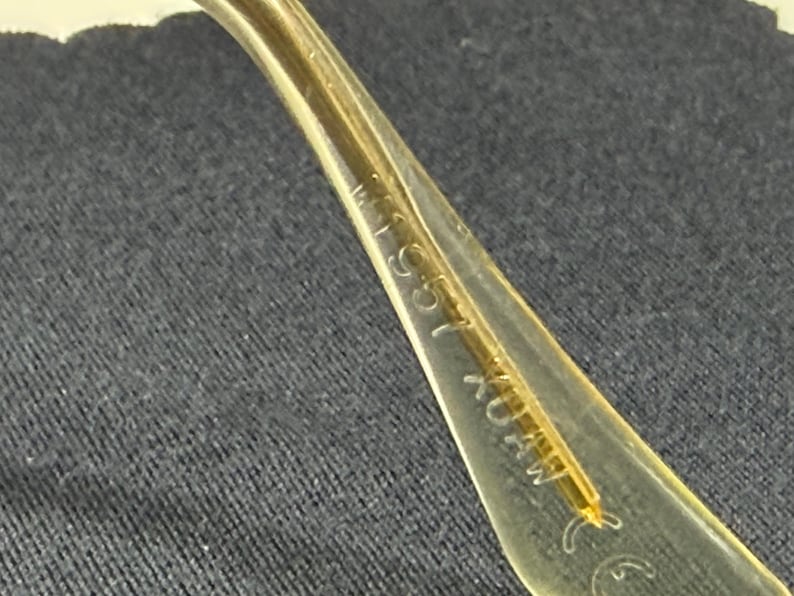 May include: A translucent yellow eyeglass temple arm featuring embossed text that reads 155 and CE. The material is smooth and semi-transparent, showing a thin internal structural wire running through the center of the curved plastic component.