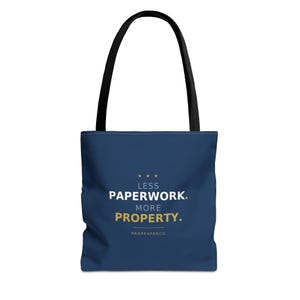 May include: Navy blue tote bag with black handles. The bag features the text "LESS PAPERWORK. MORE PROPERTY." in white and gold lettering, with three gold stars above the text. The brand name "PROPPAPERCO" is printed below the text.